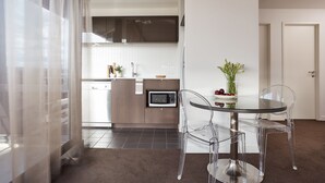 A modern kitchen with a glass table and clear chairs, a microwave, and a sink.