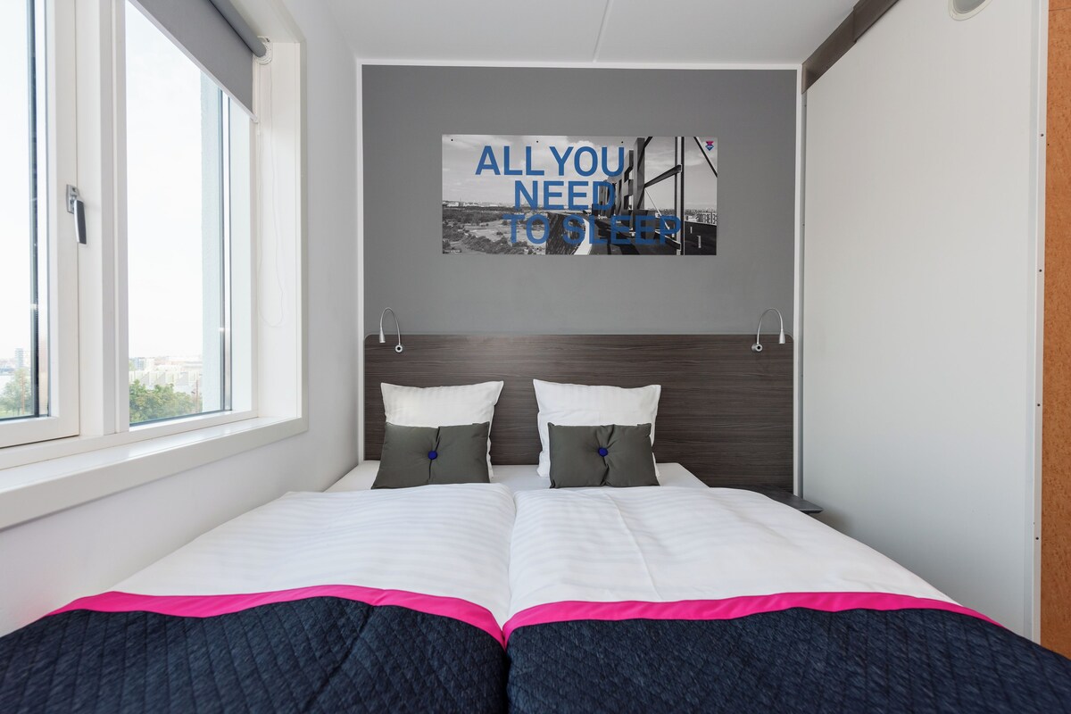 A bedroom with a large bed, a window, and a wall-mounted sign.
