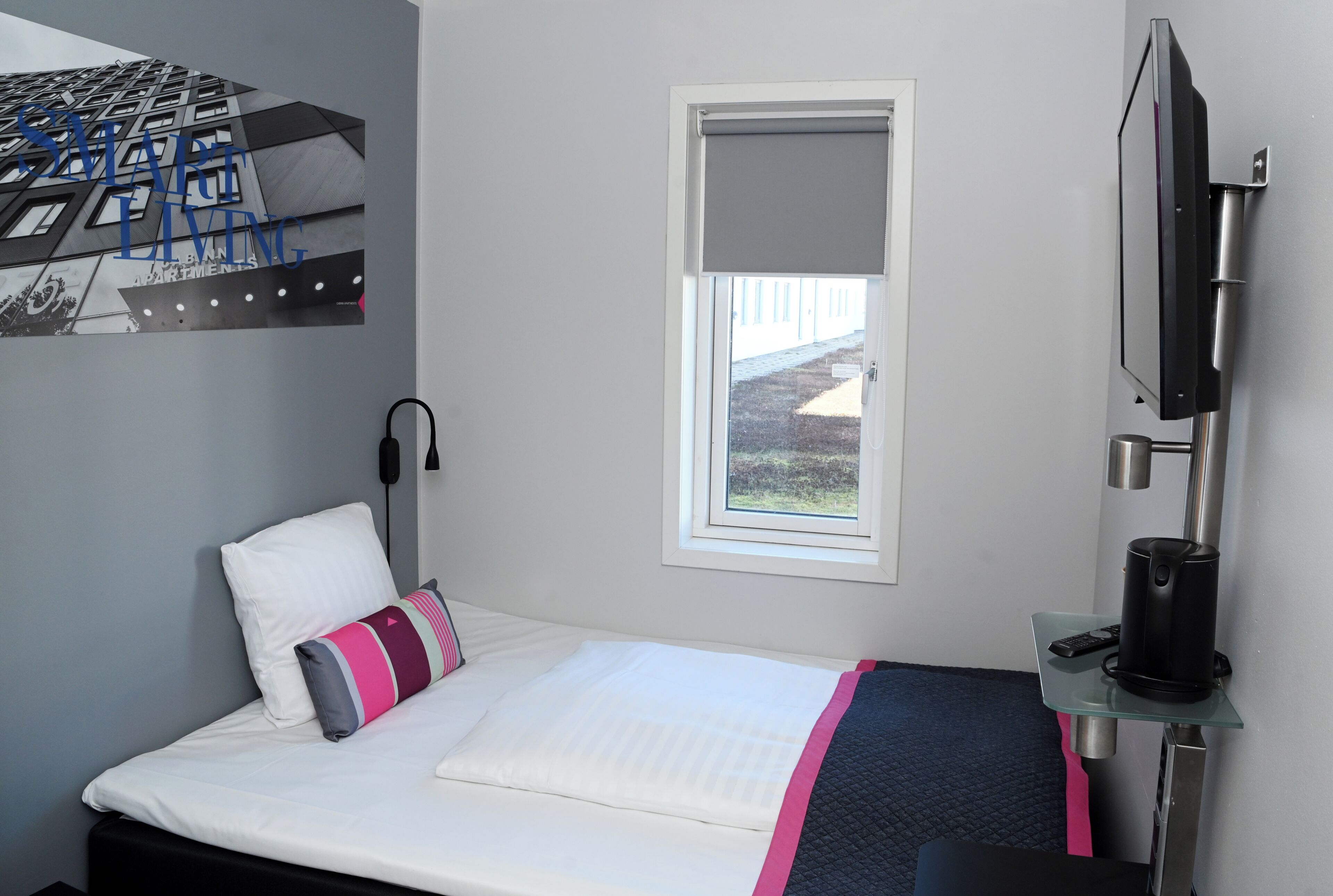 A hotel room with a bed, a window, a TV, and a coffee machine.