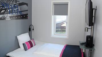 A hotel room with a bed, a window, a TV, and a coffee machine.