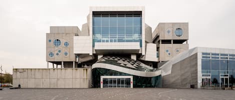 A modern building with a unique architectural design, featuring a central glass facade and multiple circular windows.