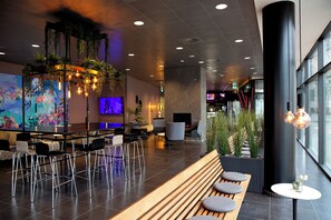 A modern interior with a bar area, seating, and a large window. - CABINN Aalborg Hotel (Aalborg)