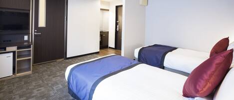 Une chambre d’hôtel avec deux lits, un bureau et une kitchenette.