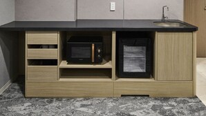 Eine Küche mit eingebauter Mikrowelle und Kühlschrank, Holzschränken und einer schwarzen Arbeitsplatte.