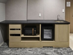 Una cocina con microondas y refrigerador integrados, armarios de madera y encimera negra.