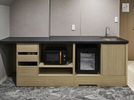 Una cocina con microondas y refrigerador integrados, armarios de madera y encimera negra.