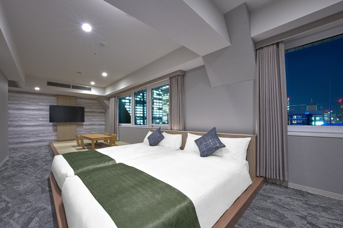 Une chambre d’hôtel avec un lit, une télévision, un bureau et une fenêtre donnant sur la ville.