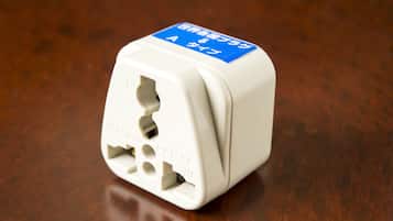 A white electrical plug with a blue label on a wooden surface.