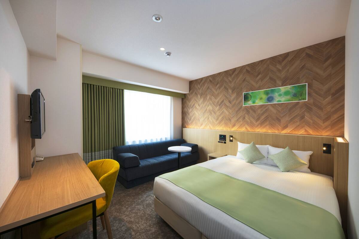 Une chambre d’hôtel avec un lit, un bureau, un canapé et une télévision.