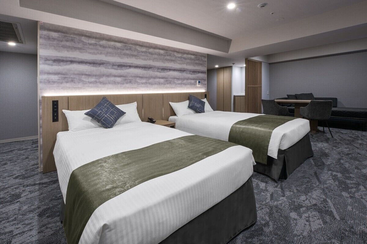 Une chambre d’hôtel avec deux lits, un bureau et un coin salon.