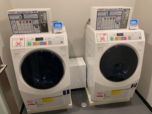 Two stacked front-loading washing machines with control panels and safety instructions.