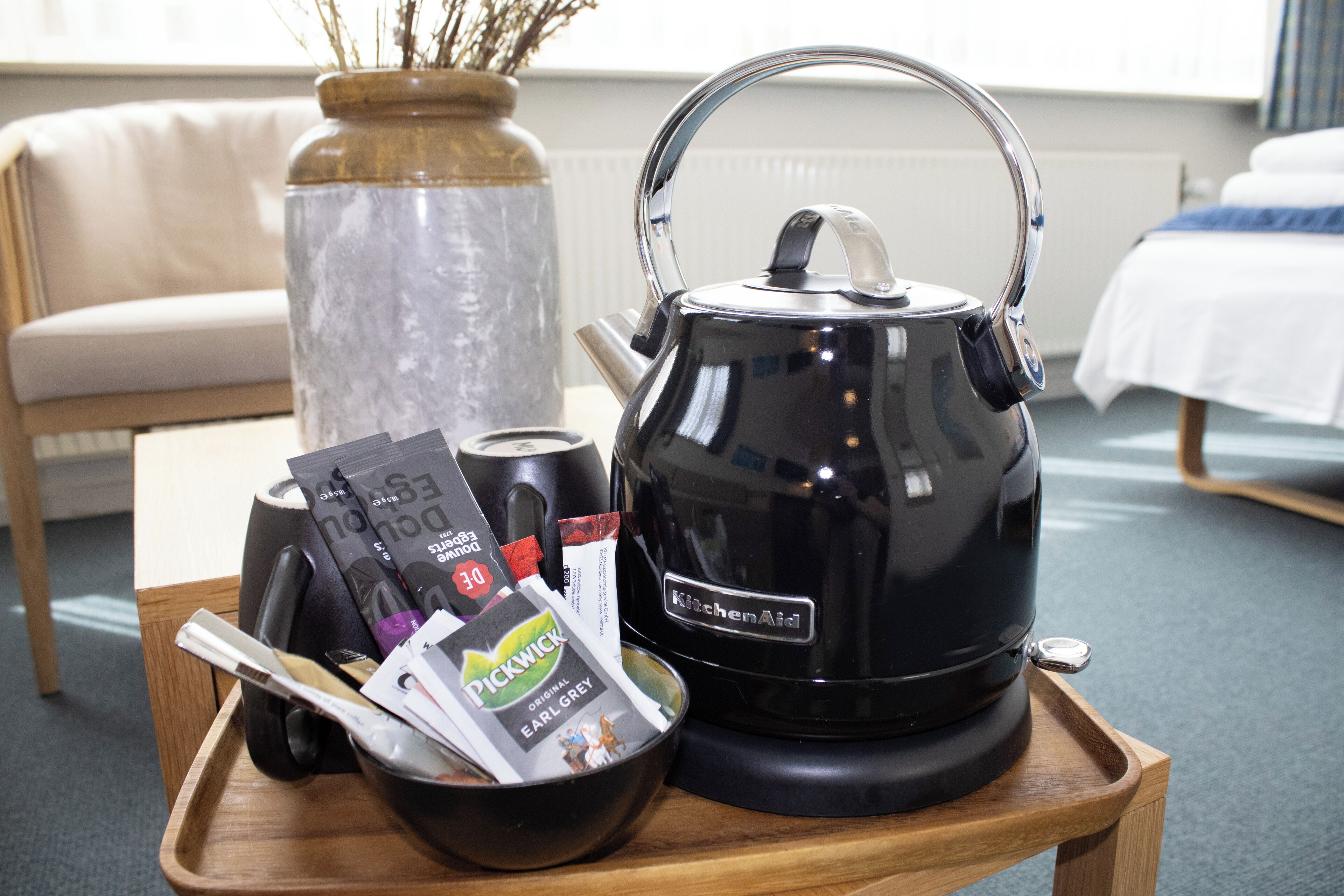 A tray with a black kettle, a bowl, and some magazines.