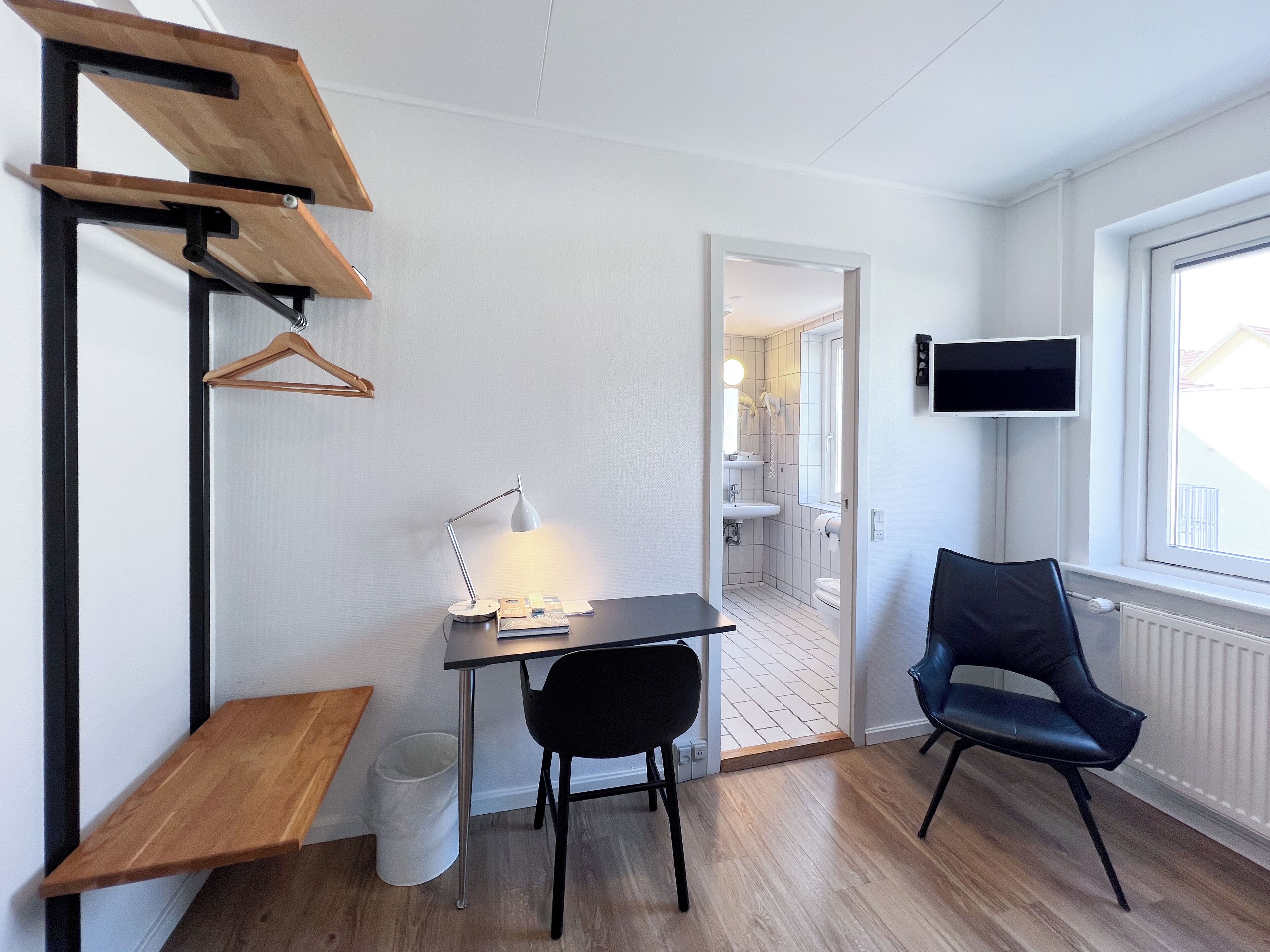 Une chambre moderne équipée d’un bureau, d’une chaise et d’un téléviseur fixé au mur.