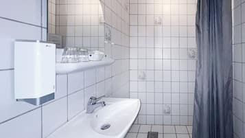 Un bagno con lavandino bianco, specchio e tenda per la doccia.