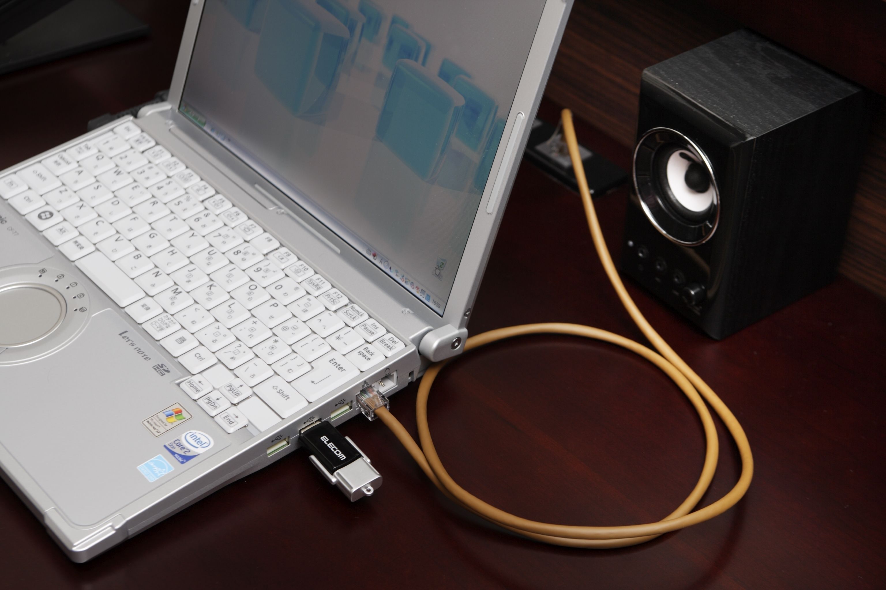 Una computadora portátil con teclado, monitor y altavoz conectado por un cable.