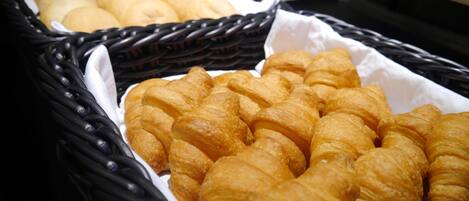 A basket of freshly baked croissants and bread rolls.