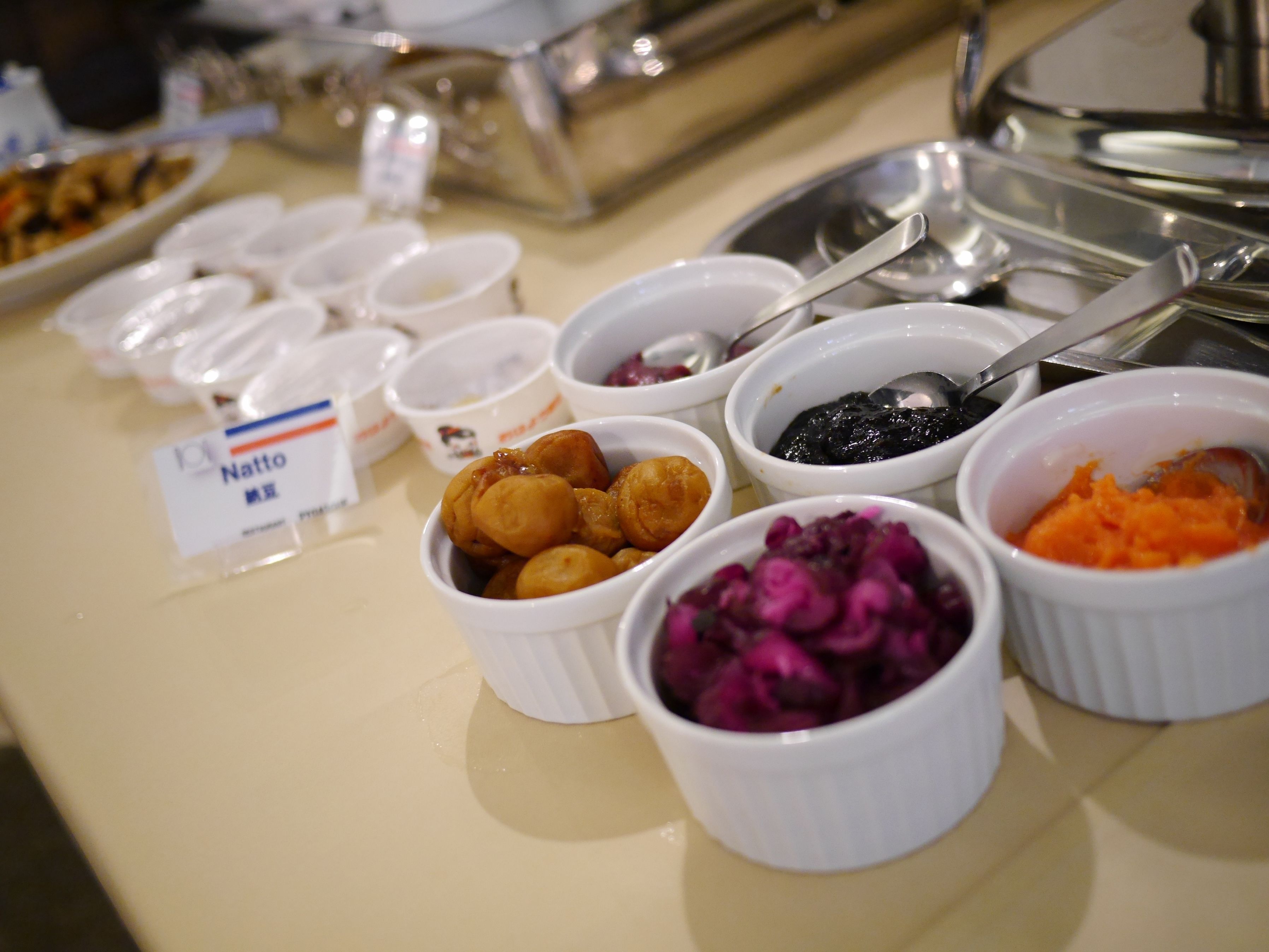A buffet table with various food items in small bowls, including what appears to be a dish with red cabbage and another with a dark sauce.