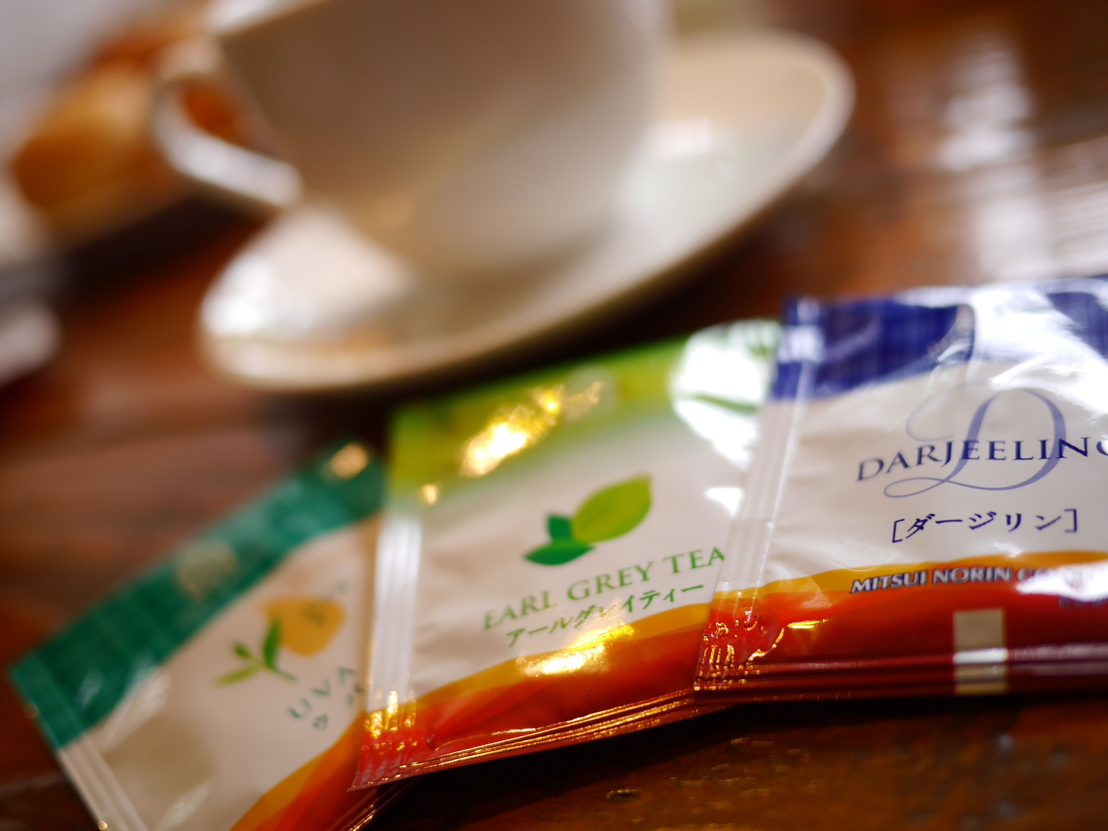A table with a white cup and saucer, and two packets of Darjeeling tea.