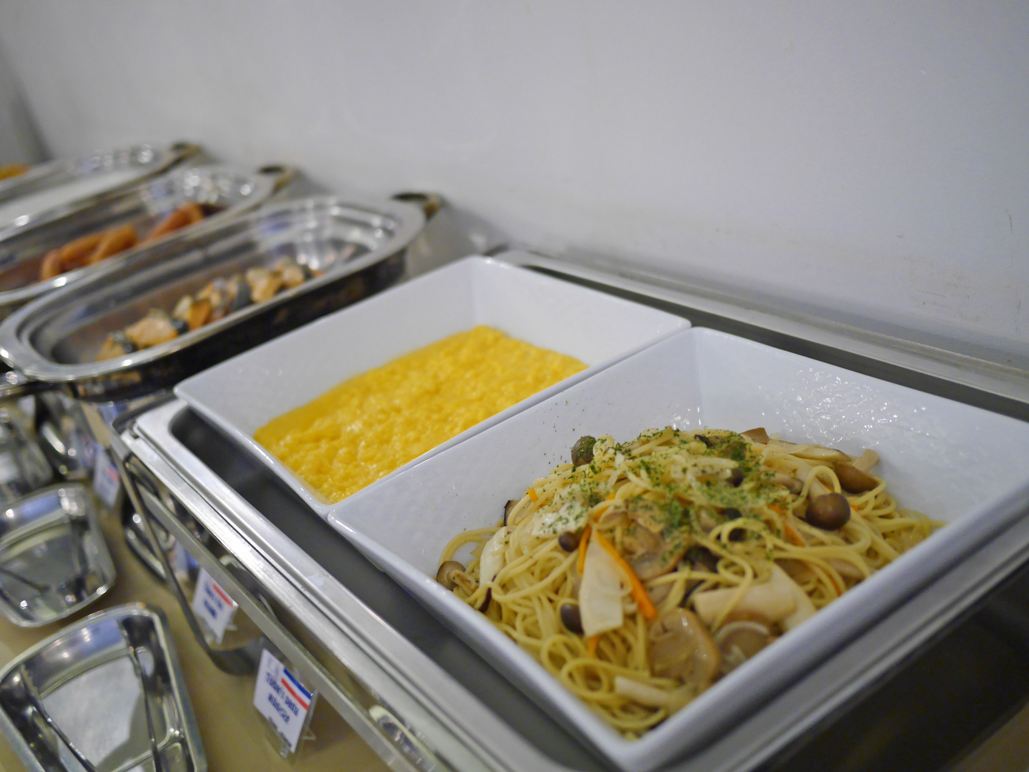 A buffet with pasta and scrambled eggs.