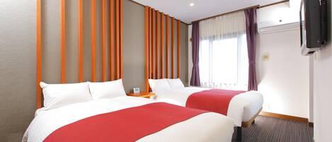 A hotel room with two beds, a flat-screen TV mounted on the wall, and a window with curtains.