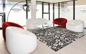 A modern interior with white and red chairs, a glass table, and a patterned rug. - Residhome Carrières La Défense (Carrieres-sur-Seine)