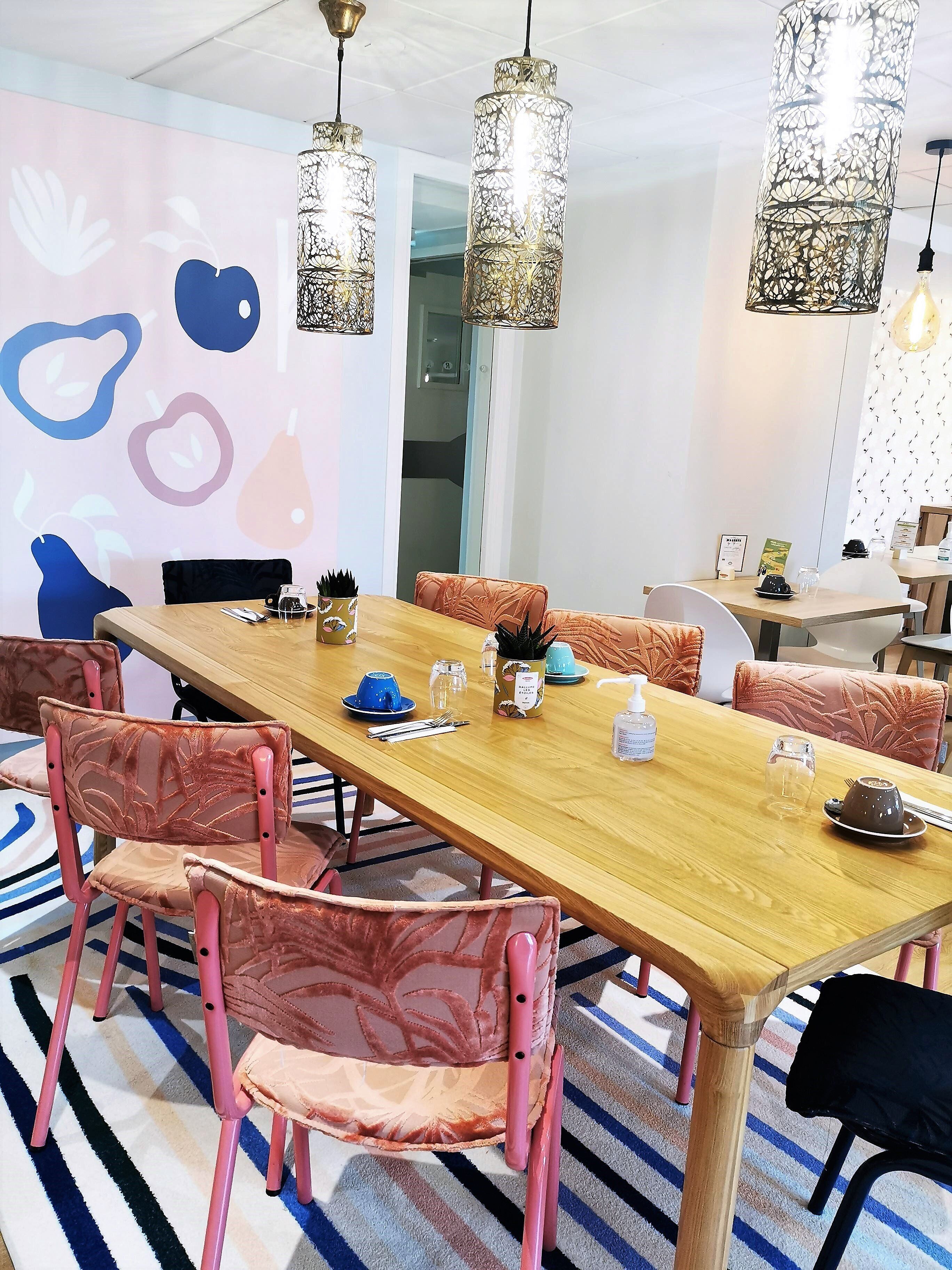 A dining area with a wooden table, pink chairs, and hanging floral light fixtures.
