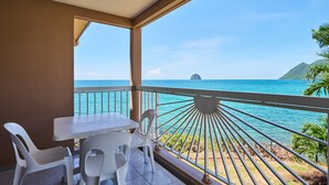 A balcony with a table and chairs, overlooking a turquoise sea and a distant island. - Diamant Beach (Le Diamant)