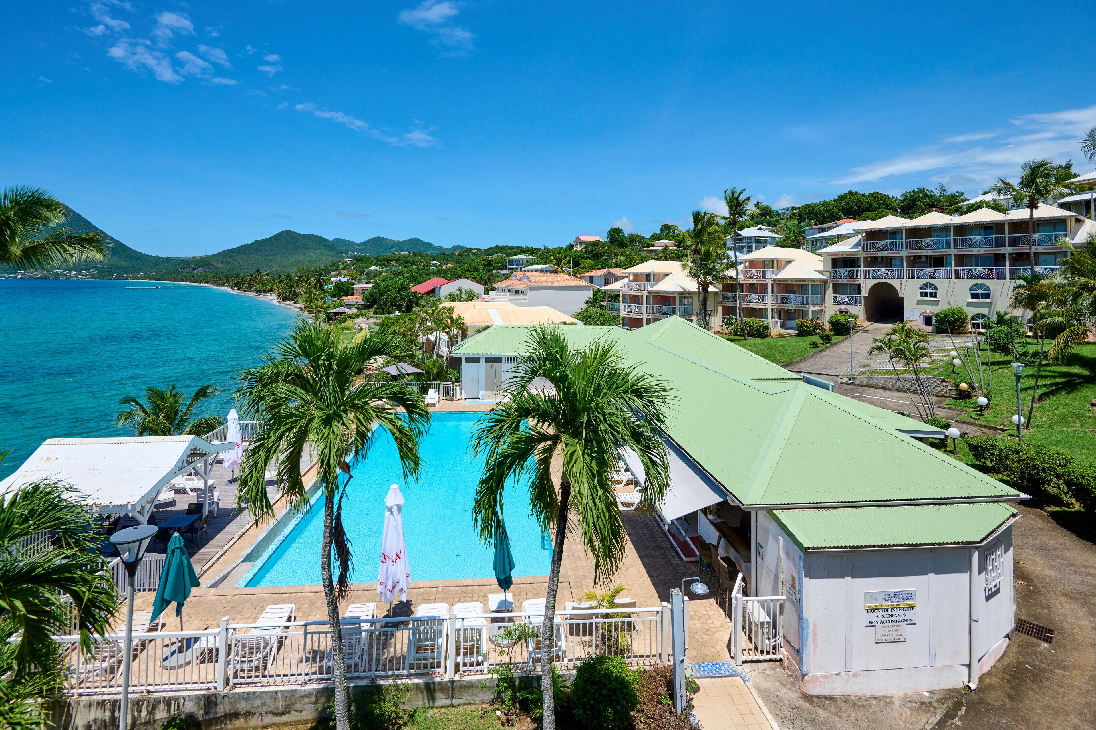 A resort with a swimming pool, lounge chairs, and a view of the ocean.