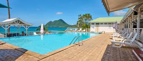 A swimming pool with lounge chairs and a view of the ocean.