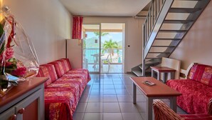 A hotel room with a sofa, a table, and a staircase. - Diamant Beach (Le Diamant)
