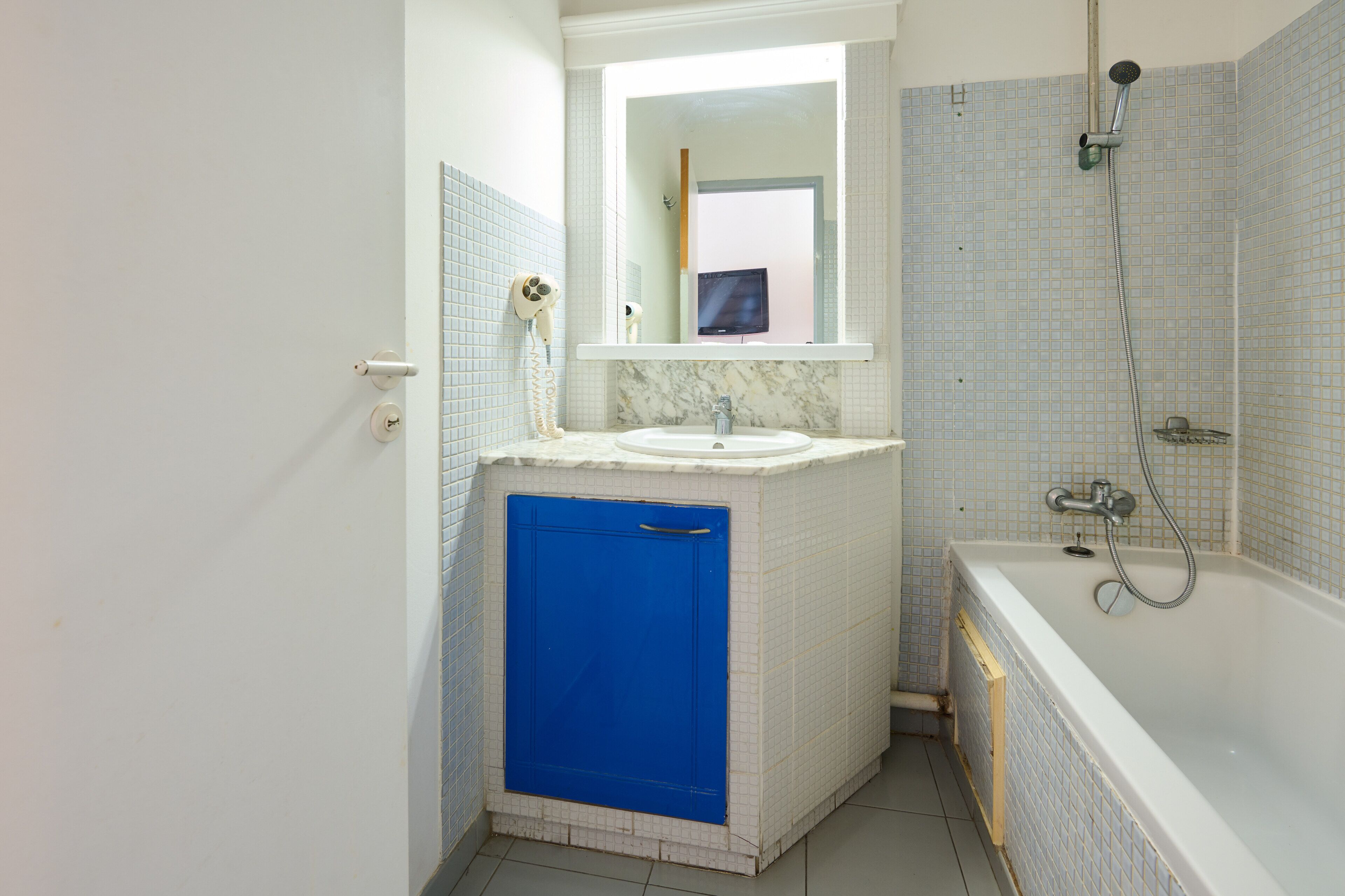 A bathroom with a sink, mirror, and shower.