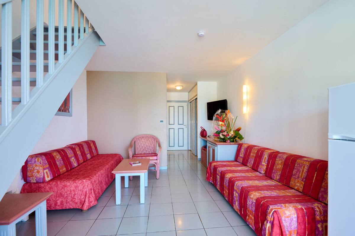 A living room with a sofa set, a chair, a small table, and a staircase.