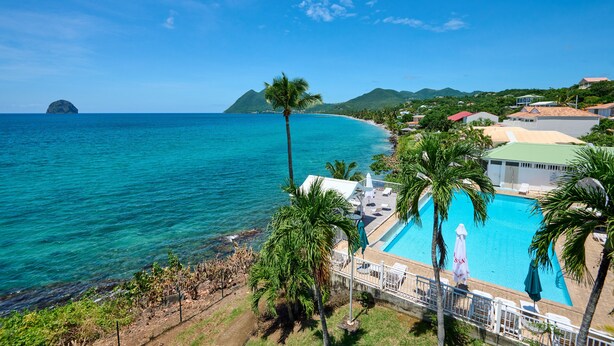 A coastal hotel with a swimming pool, beach view, and tropical landscaping. - Diamant Beach (Le Diamant)