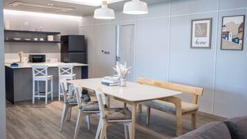 A modern kitchen with white appliances, a dining area with a white table and chairs, and a bench.