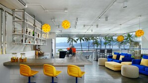A modern kitchen with a bar area, bar stools, and a view of the ocean.