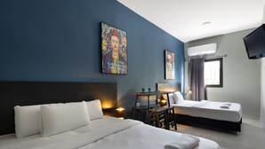 Una camera d'albergo con due letti, una scrivania e una televisione.