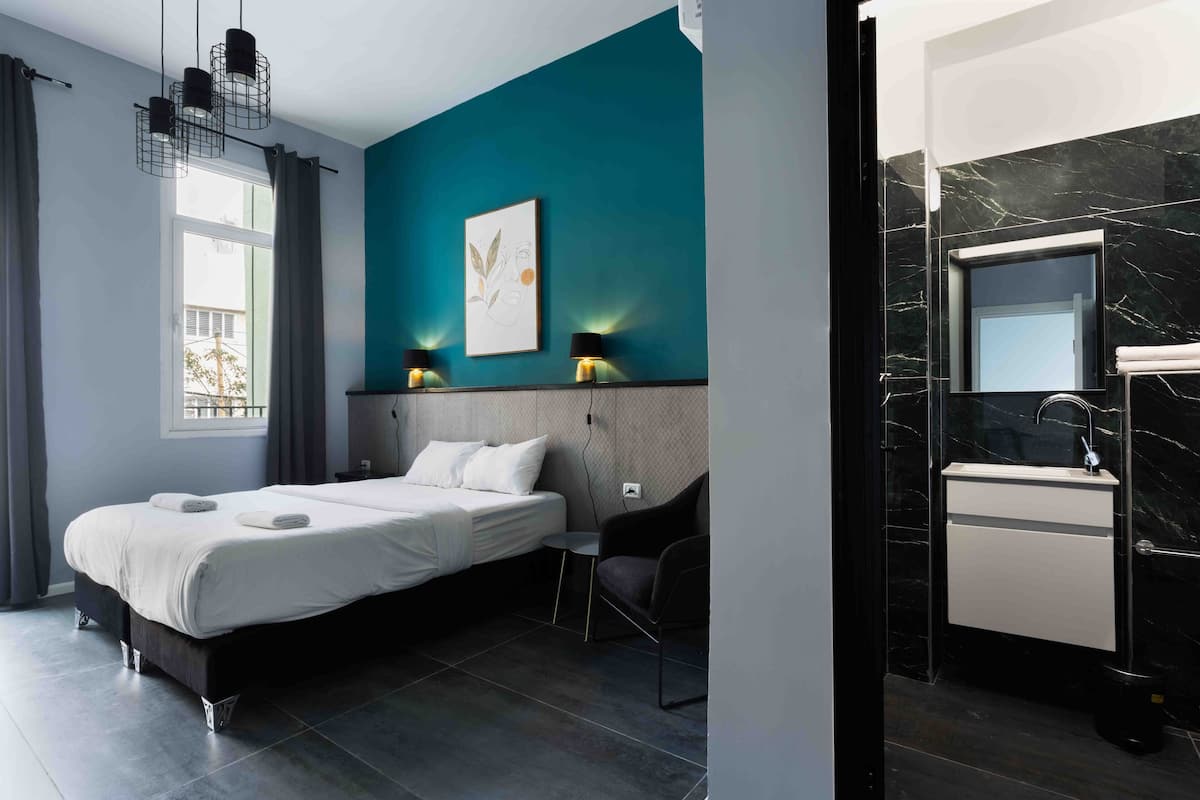 A modern bedroom with a bed, bedside lamps, a small table, and a chair.