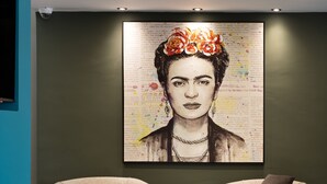 Una stanza con due poltrone, un quadro astratto di grandi dimensioni sulla parete e una telecamera di sicurezza.