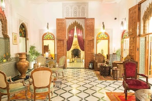 A traditional Moroccan interior with ornate wooden doors, a tiled floor, and classic furniture. - Dar El Kébira (Rabat)
