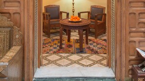 A traditional Moroccan interior with intricate woodwork, a chandelier, and a patterned rug. - Dar El Kébira (Rabat)