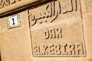 A stone wall with Arabic inscriptions and a colorful numbered sign. - Dar El Kébira (Rabat)