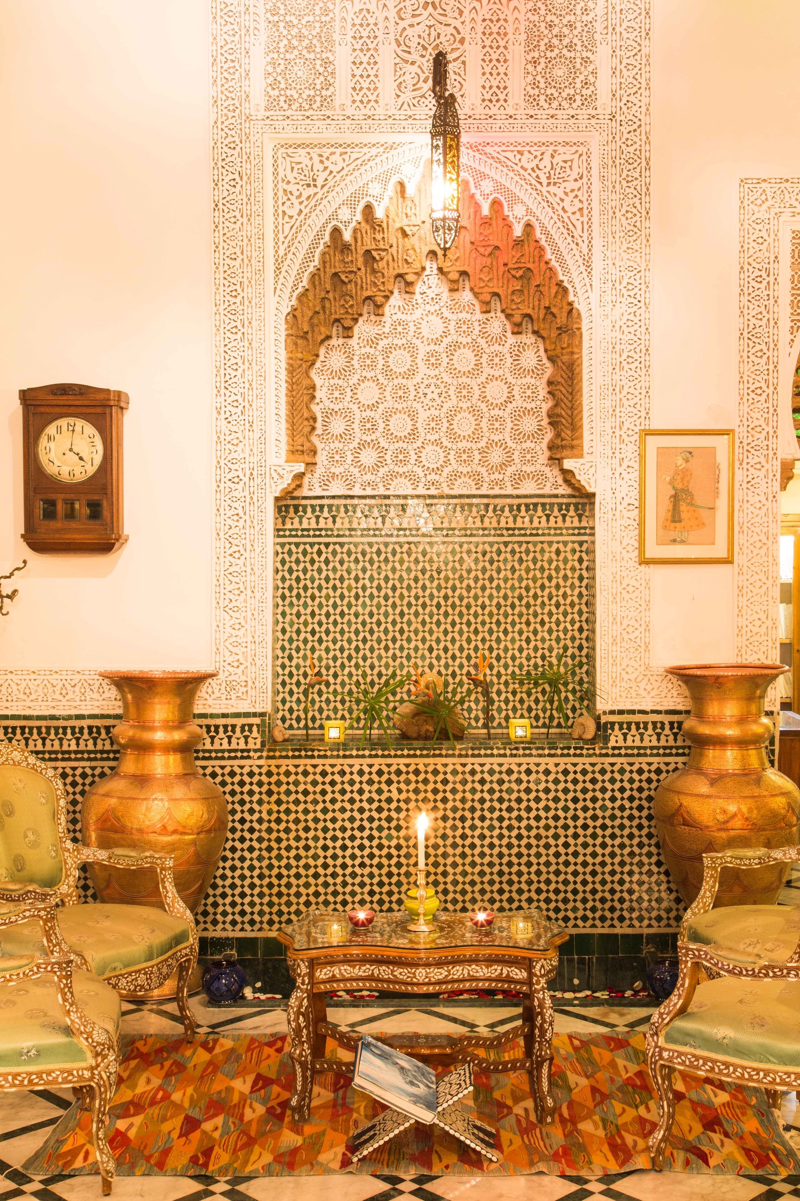 A traditional Moroccan interior with ornate tile work, a clock, and classic furniture.