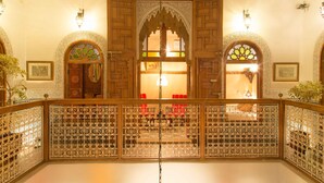 A traditional interior with ornate wooden doors, intricate lattice work, and a balcony with a railing. - Dar El Kébira (Rabat)