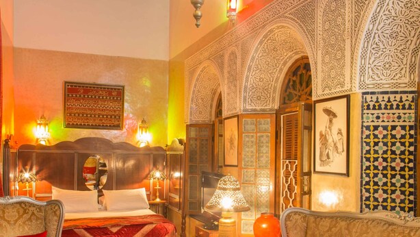 A traditional Moroccan interior with a bed, sofas, a coffee table, and ornate wall decorations. - Dar El Kébira (Rabat)