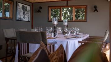 A dining area with a table set for a meal, chairs, and framed pictures on the wall.