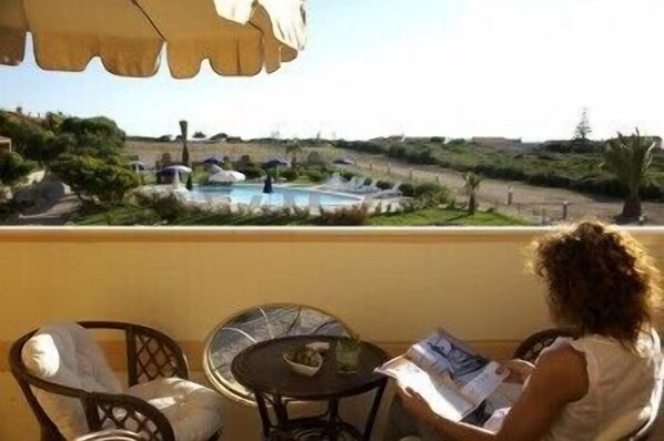 Un balcon donnant sur une piscine, avec des chaises et une table.