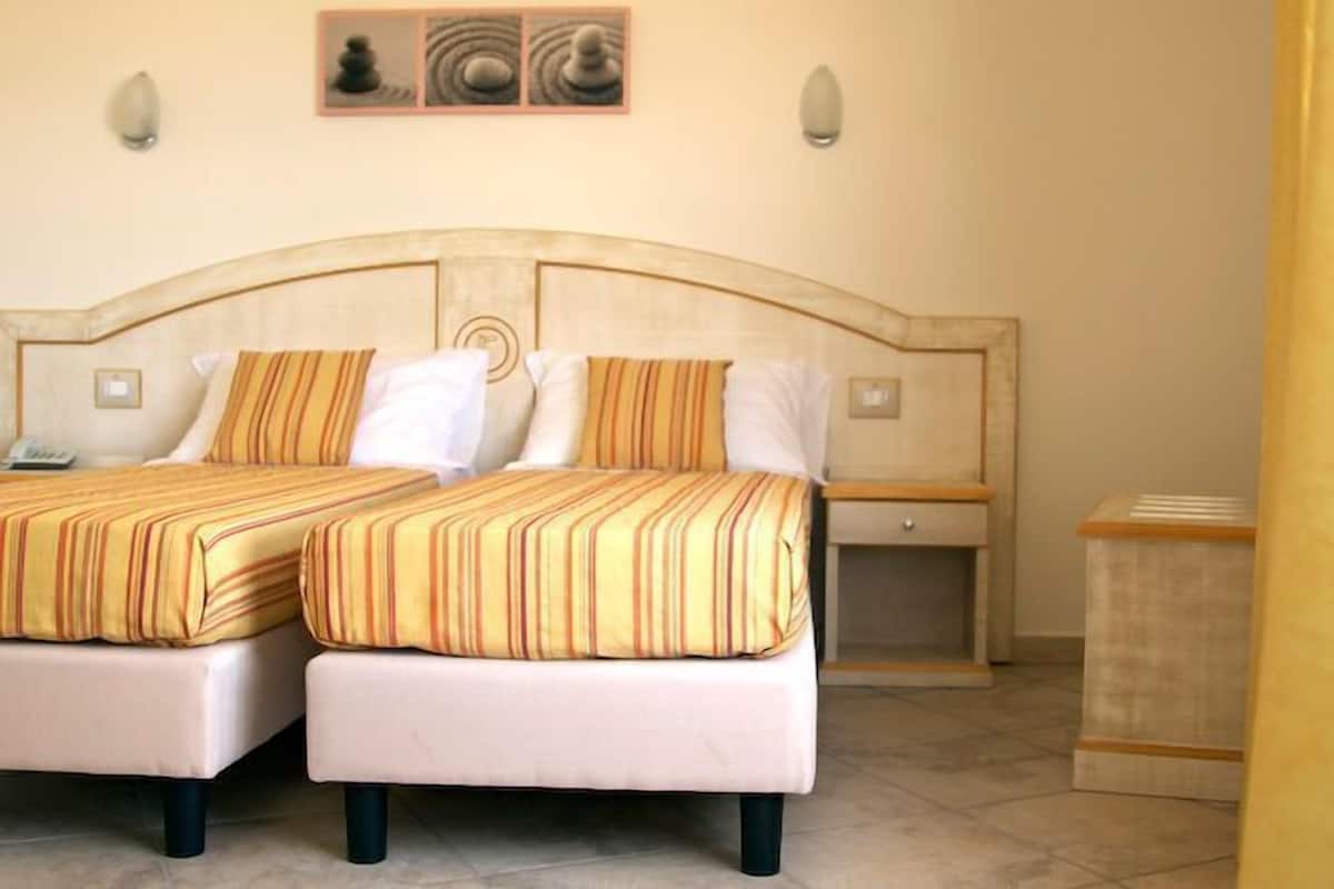 A double bed with striped bedding, a bedside table, and a nightstand.