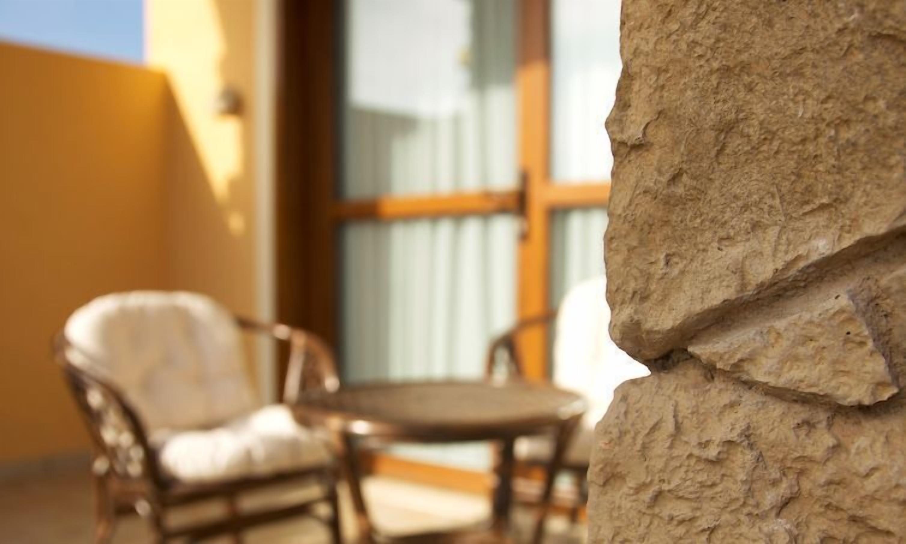A stone wall with a wooden chair and a small table, suggesting a patio or outdoor seating area.