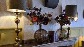 A fireplace with decorative items, including a vase with flowers and a candle. - Hotel Arcen (Arcen)