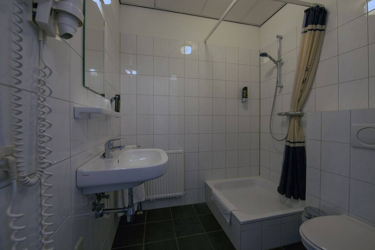 A small, clean bathroom with a white sink, a bathtub, and a toilet.